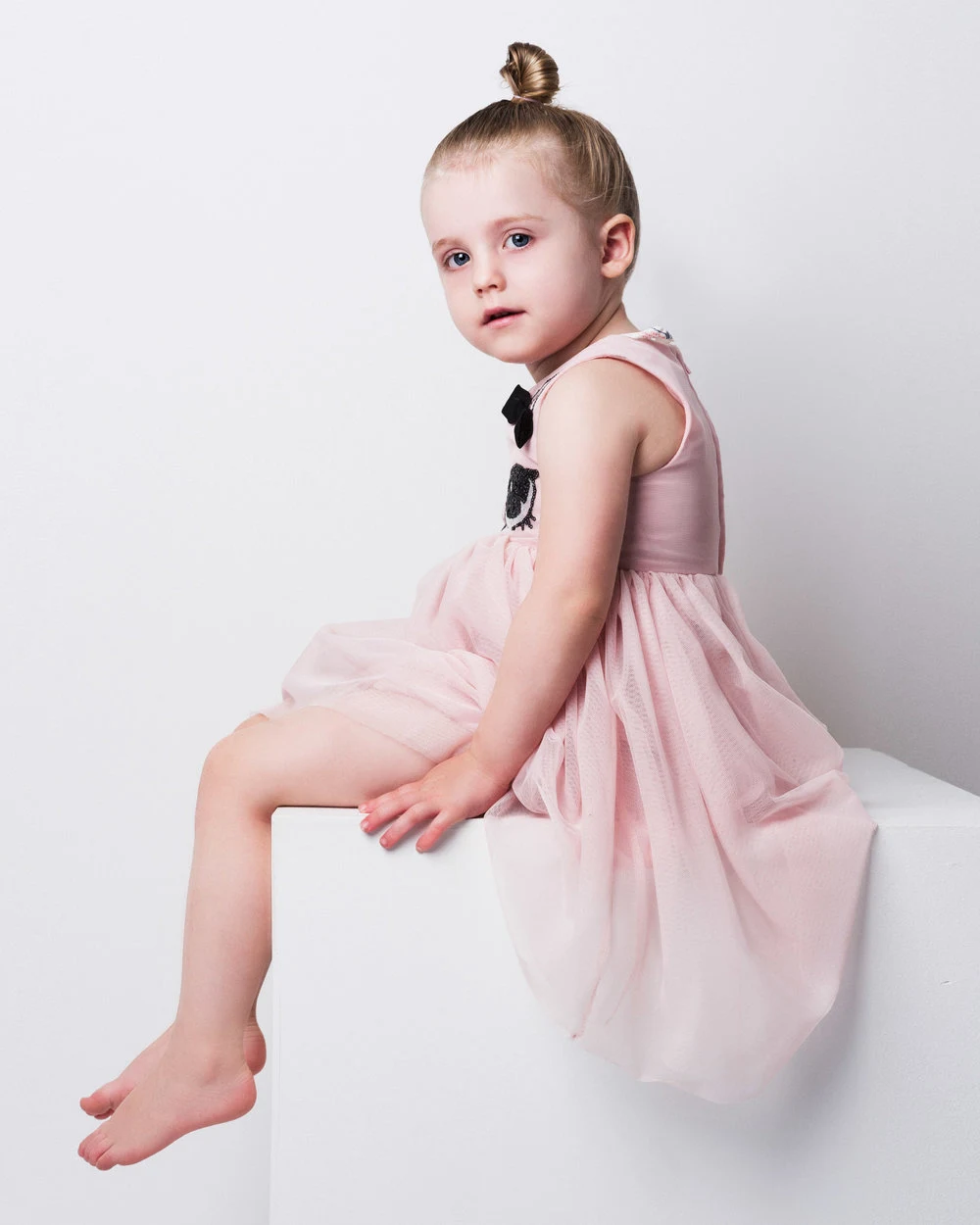 Child in a pink dress against a white studio backdrop