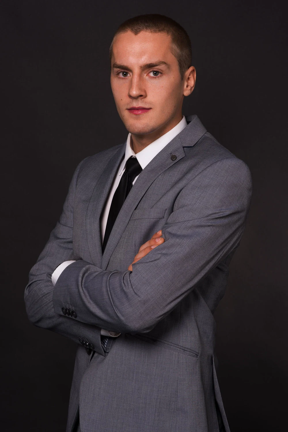 Studio portrait of a man in a suit with folded arms