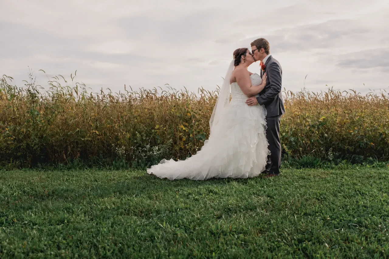 Wedding couple embracing at the edge of a field